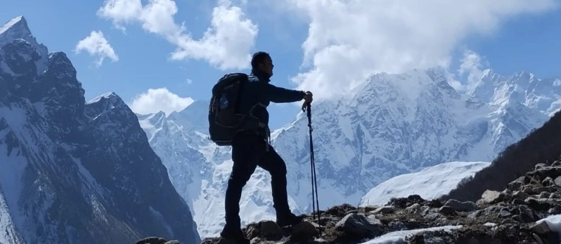 A trekker silhouetted against the snow-capped peaks of the Manaslu range